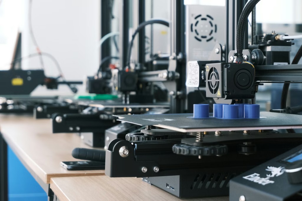 Row of FDM 3D printers on a workbench actively printing parts, showing in-house production capacity